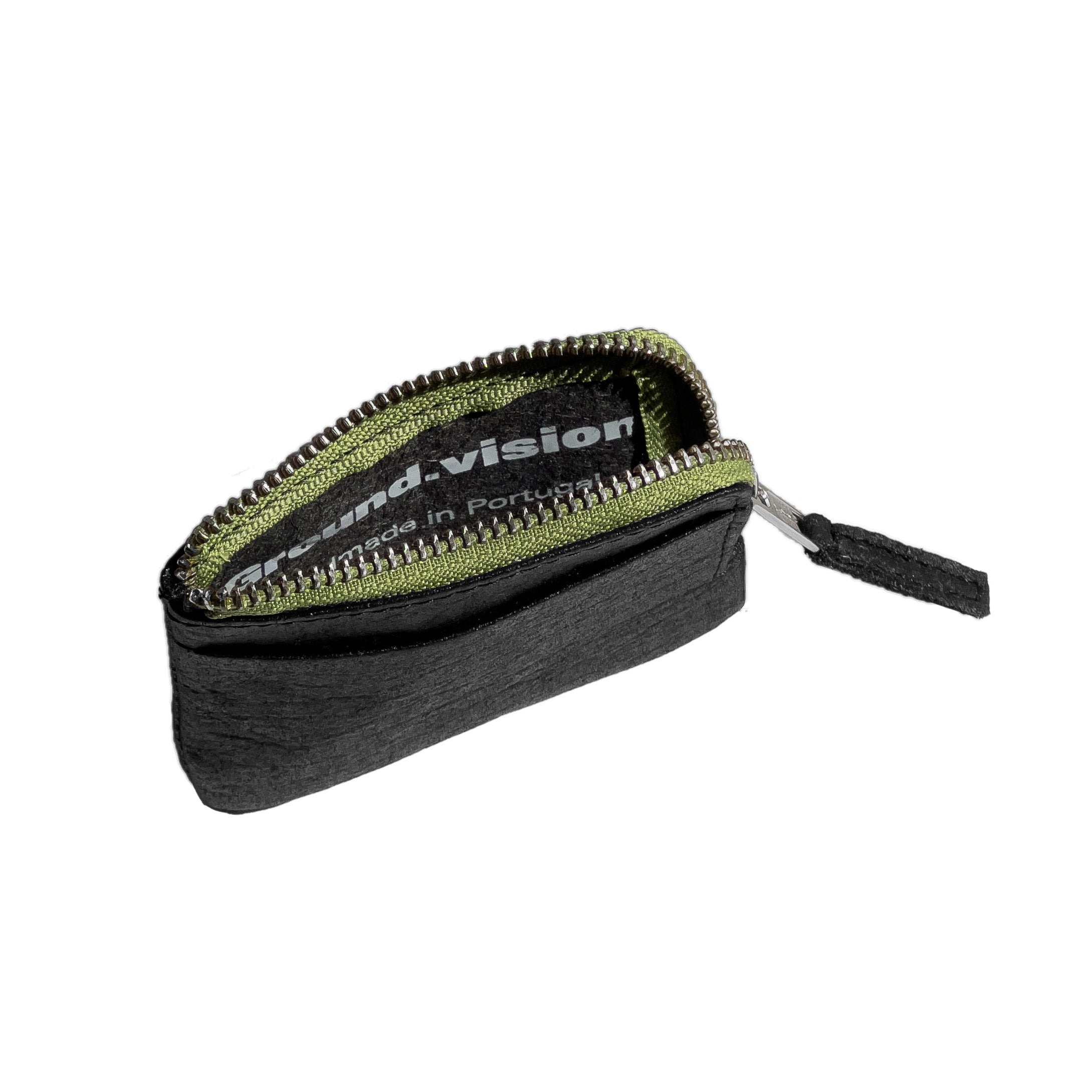 An angled view of The Zippered Ground wallet, showing the open interior with a visible printed label that reads “Ground.vision Handmade in Portugal.” The wallet features a black Piñatex exterior with a green zipper lining and durable aluminum zipper teeth. The minimalist design highlights the wallet’s compact structure and sustainable craftsmanship.